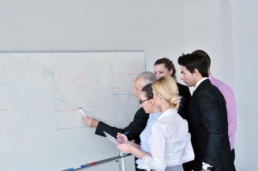 Senior male business man giving a presentation at a  meeting at modern light office on a table board