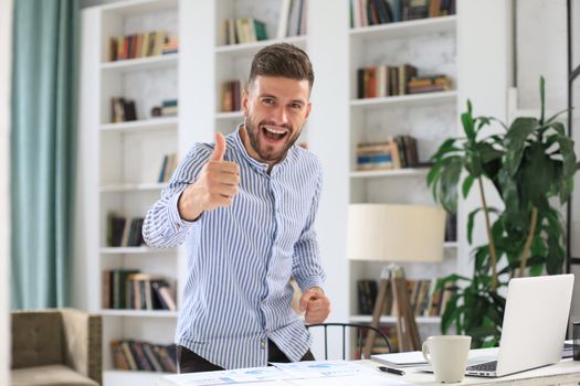 Businessman showing OK sign with his thumb up. Selective focus on face