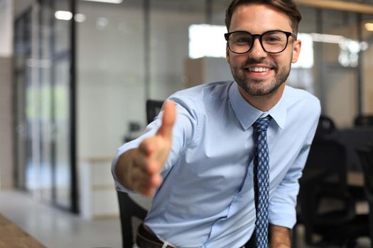 Business man with an open hand ready to seal a deal in office