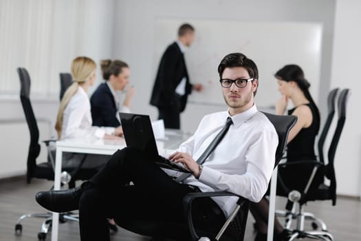 Portrait of a handsome young business man with people  in background at office meeting