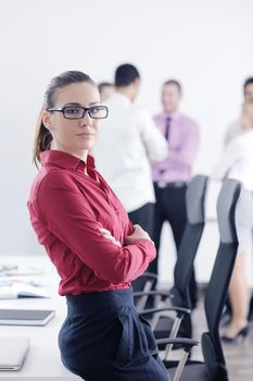 Successful business woman standing with her staff in background at modern bright office