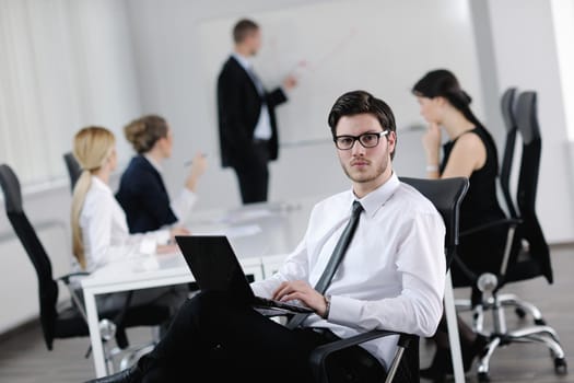 Portrait of a handsome young business man with people  in background at office meeting