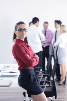 Successful business woman standing with her staff in background at modern bright office