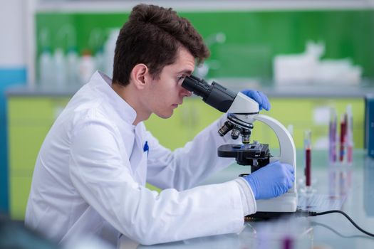 Young student scientist looking through a microscope while doing some research in the laboratory