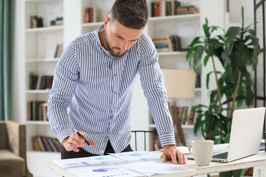 Young modern business man analyzing data using laptop while working in the office
