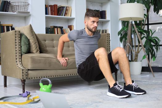 Handsome man doing sport exercise at home during quarantine. Concept of healthy life