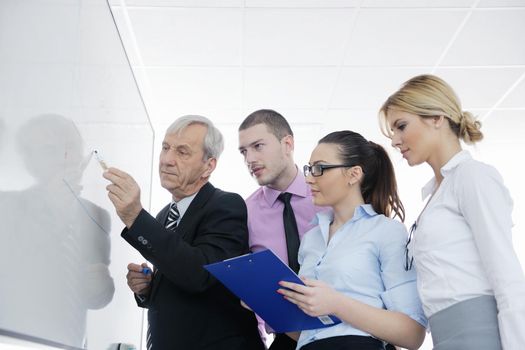 Senior male business man giving a presentation at a  meeting at modern light office on a table board