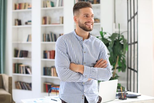 Portrait of happy businessman with arms crossed standing in office