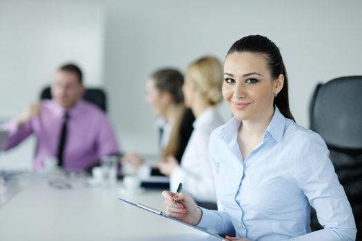 Successful business woman standing with her staff in background at modern bright office