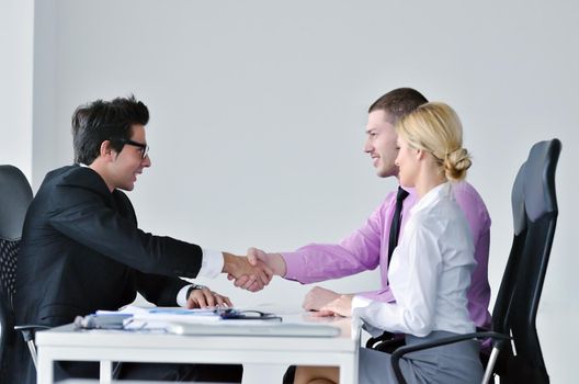 Group of young business people sitting in board room during meeting and discussing with paperwork