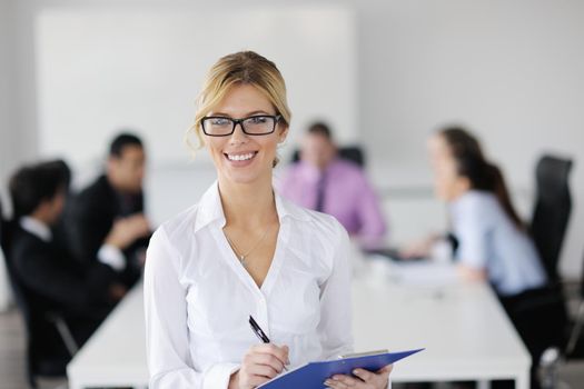 Successful business woman standing with her staff in background at modern bright office