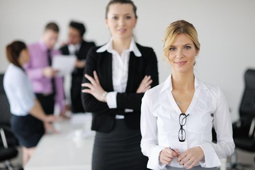 Successful business woman standing with her staff in background at modern bright office