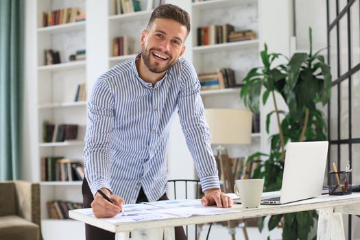 Young modern business man analyzing data using laptop while working in the office
