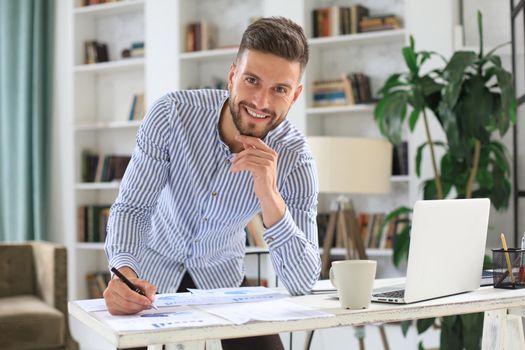 Young modern business man analyzing data using laptop while working in the office
