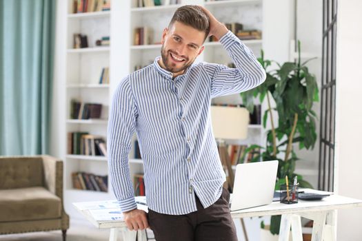 Portrait of happy businessman standing in modern bright office