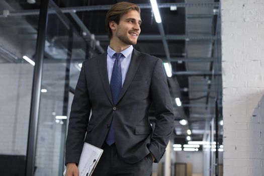 Handsome young businessman walking in office corridor