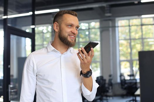 Handsome business man using a voice recognition app in office