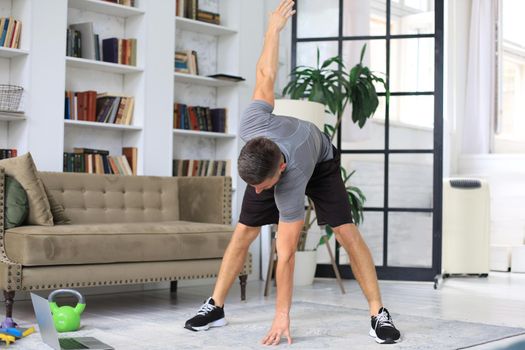 Handsome man doing sport exercise at home during quarantine. Concept of healthy life