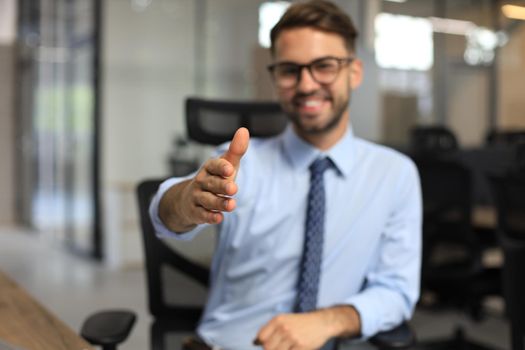 Business man with an open hand ready to seal a deal in office