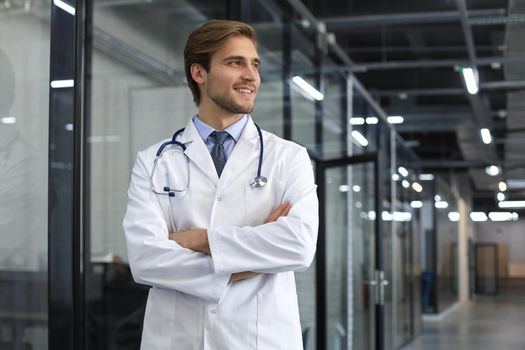 Portrait of doctor standing in hospital corridor wearing lab coat and stethoscope
