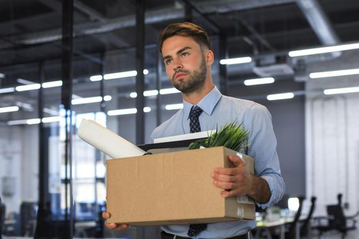 Sad dismissed worker is taking his office supplies with him from office