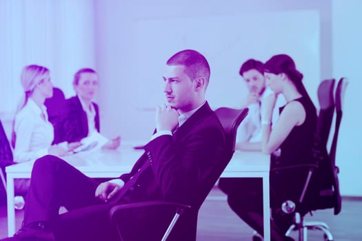 Portrait of a handsome young business man with people  in background at office meeting