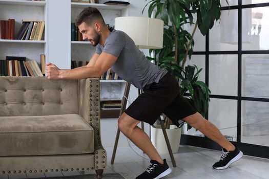 Handsome man doing sport exercise at home during quarantine. Concept of healthy life