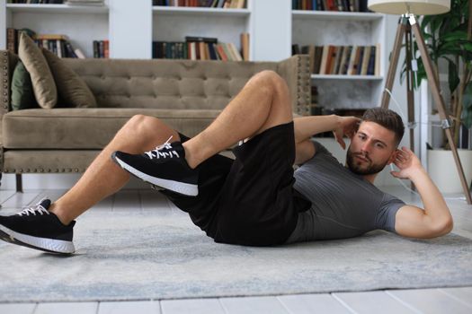 Handsome man doing abs exercises at home during quarantine. Concept of healthy life