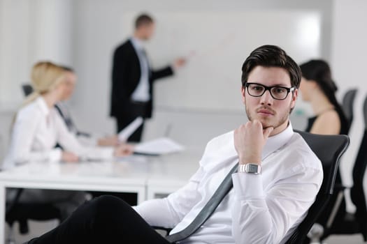 Portrait of a handsome young business man with people  in background at office meeting