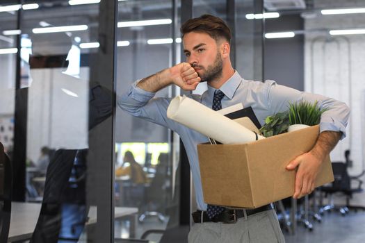 Sad dismissed worker is taking his office supplies with him from office