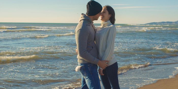 Cool Couple Laughing and hugging In Front Of Beach at beautiful autumn day