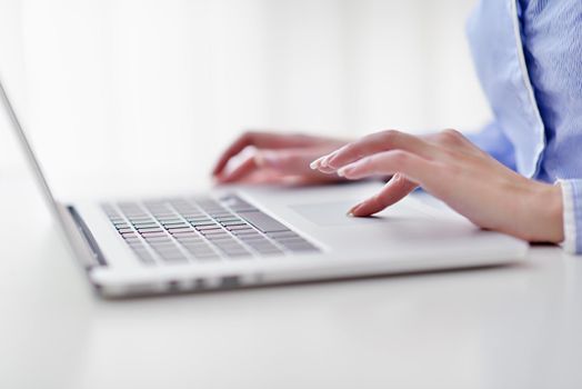 portrait of Young pretty business woman work on  notebook computer  in the bright modern office indoors