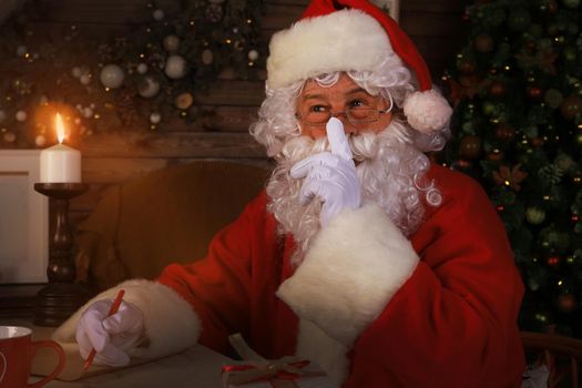 Portrait of Santa Claus keeping forefinger by his mouth and looking at camera