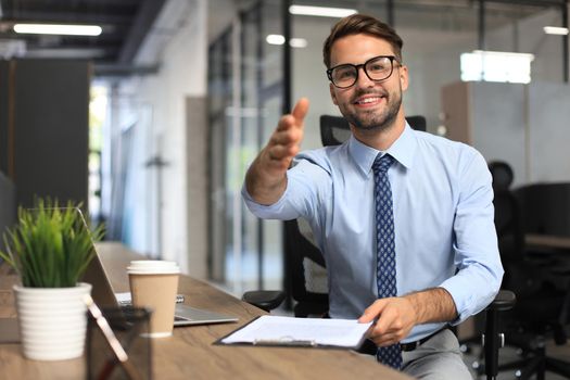 Business man with an open hand ready to seal a deal in office