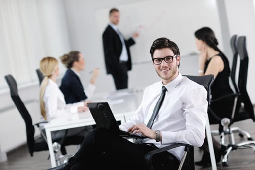 Portrait of a handsome young business man with people  in background at office meeting