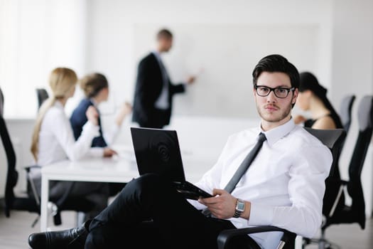 Portrait of a handsome young business man with people  in background at office meeting