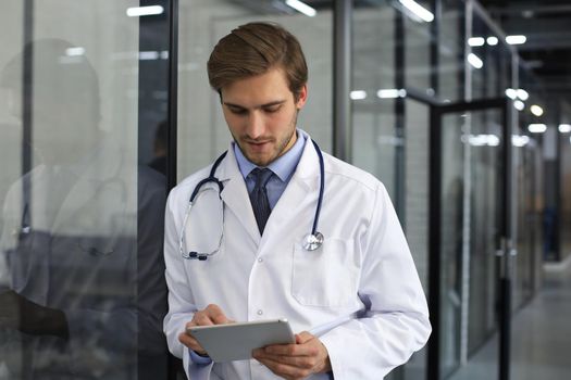 Portrait of doctor standing in hospital corridor wearing lab coat and stethoscope