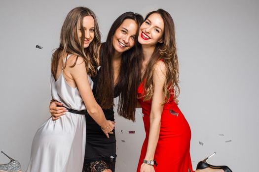 Happy beautiful women hugging while celebrating together, isolated on grey background. Party concept