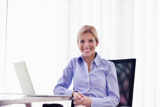 portrait of Young pretty business woman work on  notebook computer  in the bright modern office indoors