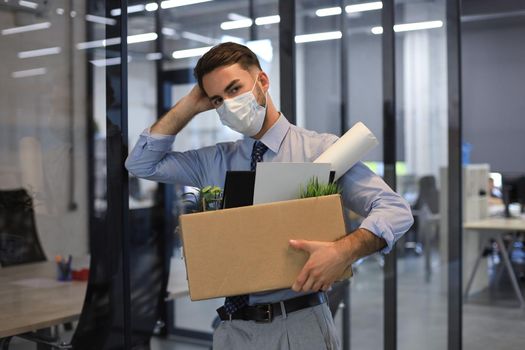 Dismissal employee in an epidemic coronavirus. Dismissed worker going from the office with his office supplies