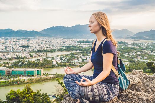 Young woman meditating over ancient city landscape on sunrise Copy space.