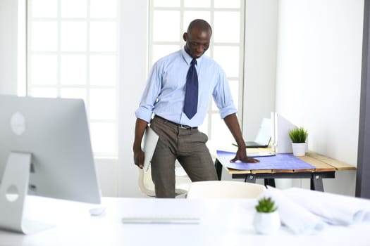 African american architect working with computer and blueprints in office.