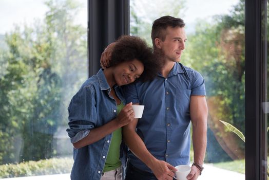 romantic happy young multiethnic couple enjoying morning coffee by the window in their luxury home