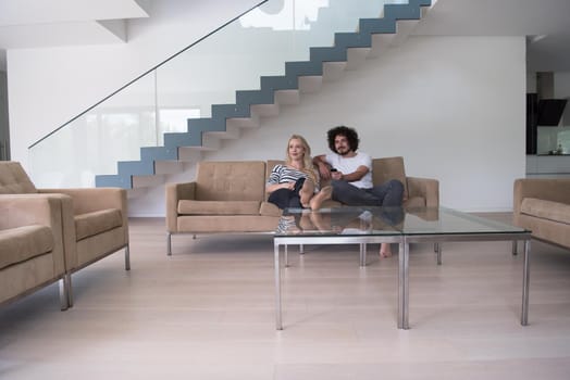 Young couple on the sofa watching television together in their luxury home