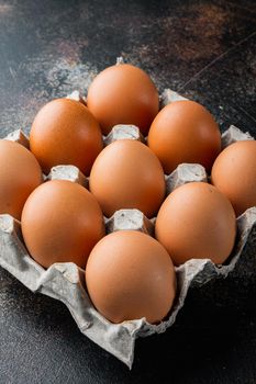 Raw chicken eggs in egg box set, on old dark rustic background