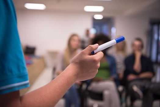 close up of teacher hand with marker while teaching lessons in school classroom to multiethnic students