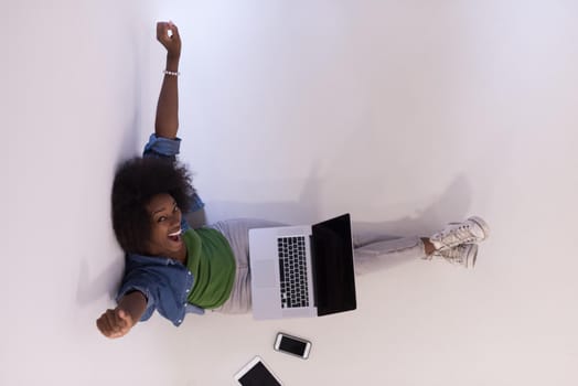 Portrait of happy young african american woman sitting on floor with laptop top view