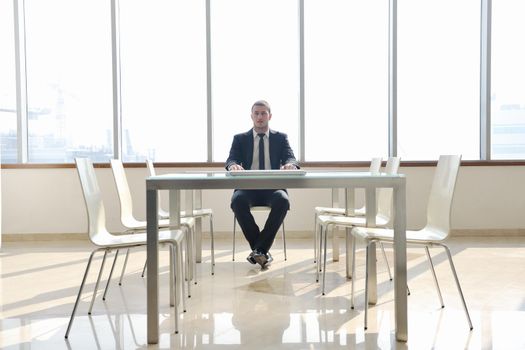 young business man lawyer with laptop alone in big bright   conference room