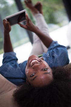 Young african american woman at home relaxing in her luxury lliving room reading a digital tablet PC surf internet and work