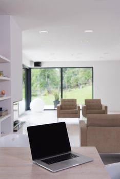 Notebook with blank screen on table in luxury living room.